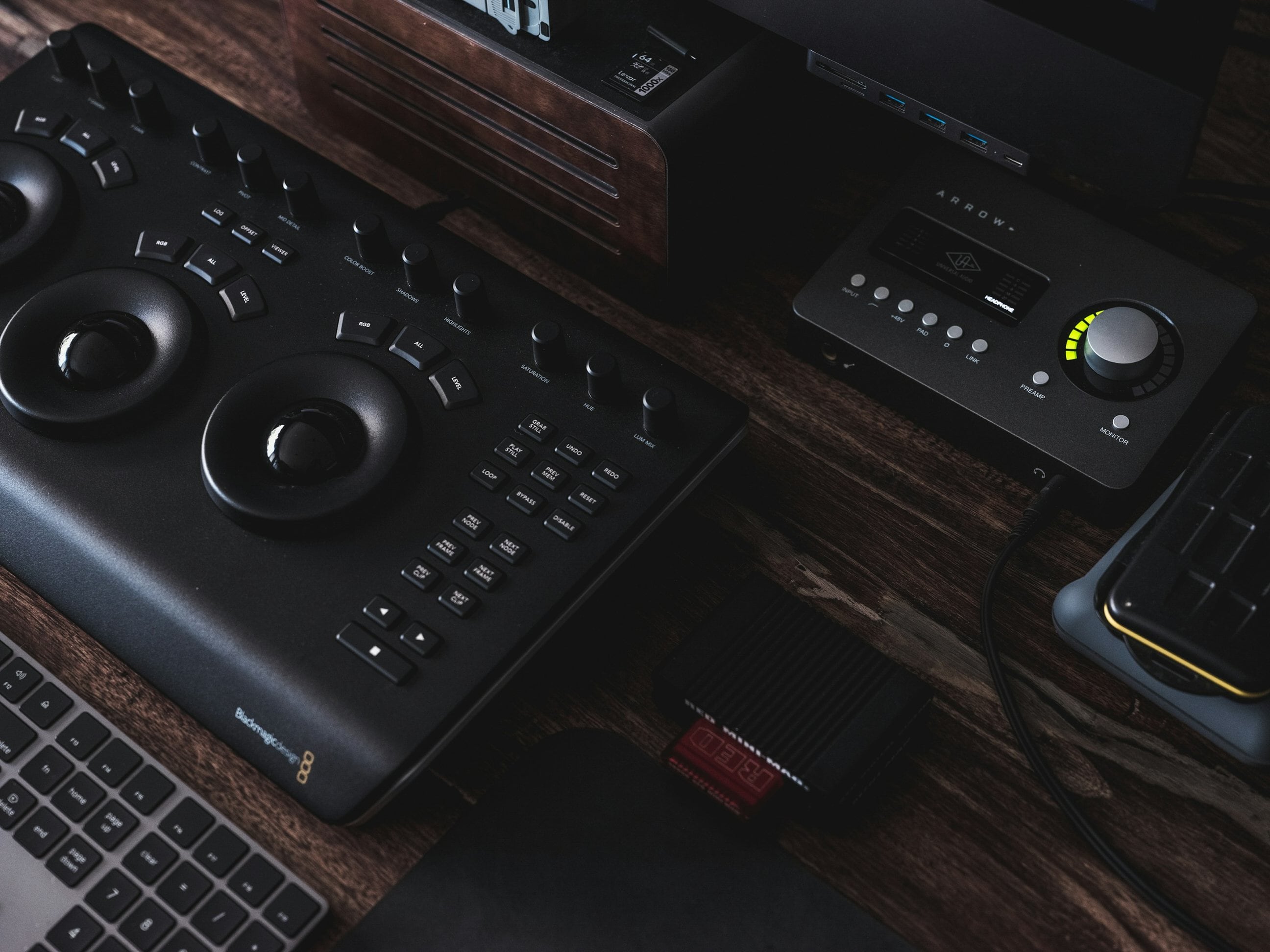 A color grading panel and an audio interface on a wooden editing desk